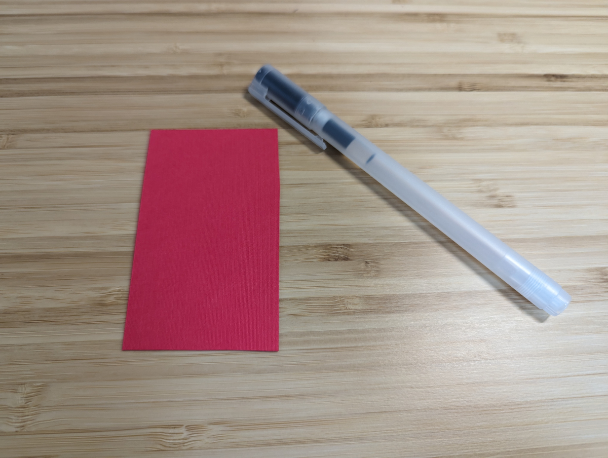 A red rectangle of paper with a pen sitting beside it.