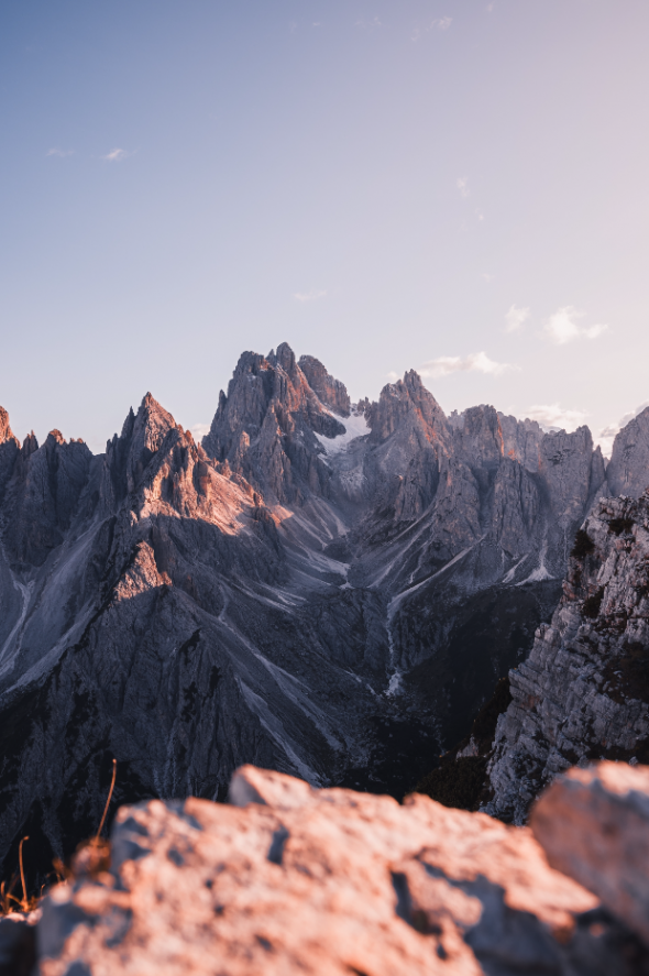 Mountain Majesty: Alpine glow on rugged mountain peaks during sunset, with a focus on rocky foreground.