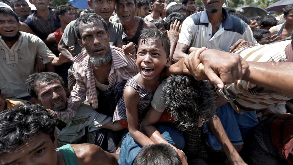 A child in Myanmar terrified and screaming with a ton of other people around looking scared and confused.