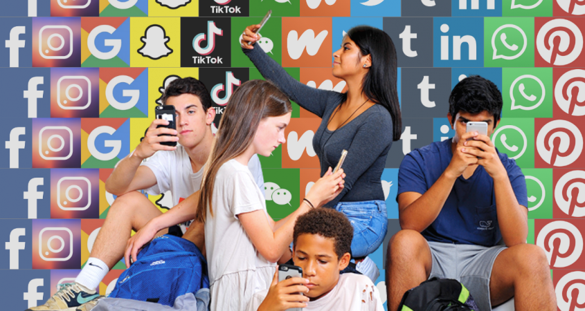 A group of teens all on their phones in front of a wall plastered with the logos of social media platforms.