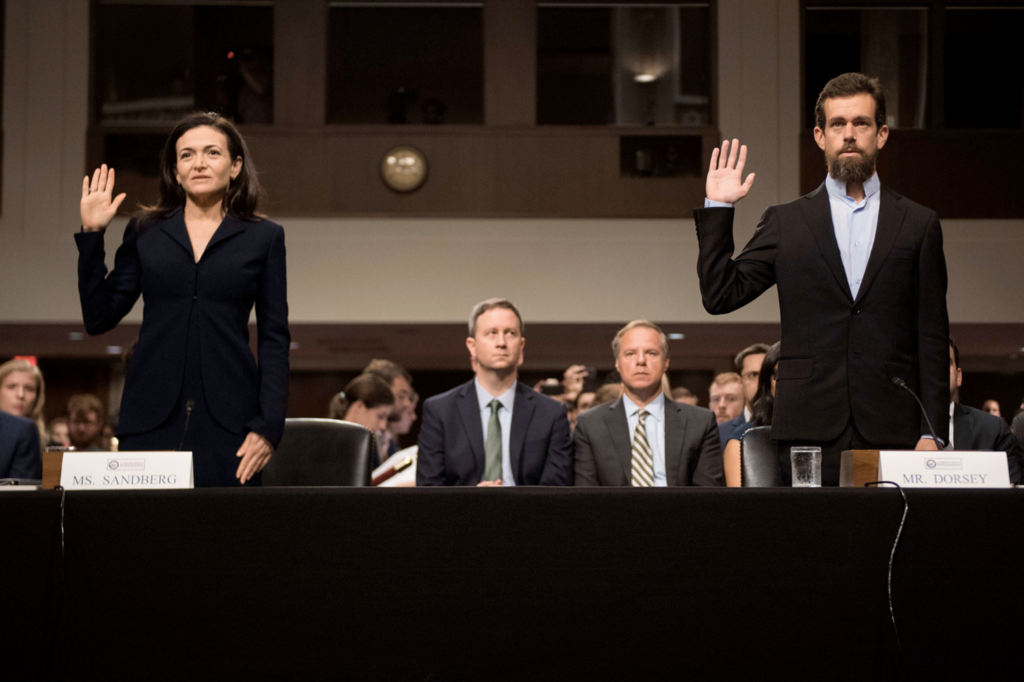 Sheryl Sandberg and Jack Dorsey raising their right hands as they testify in front of Congress.