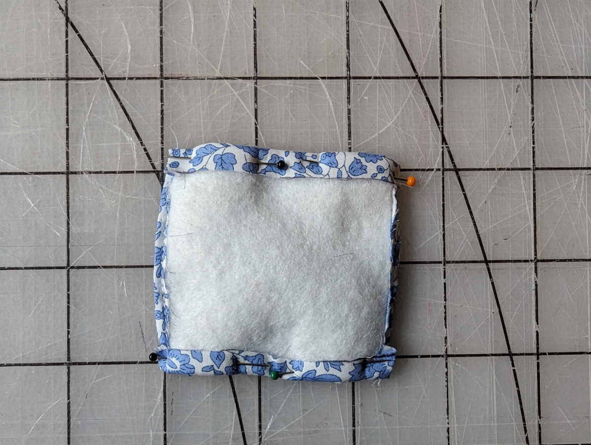 Fabric folded around a square of felt.
