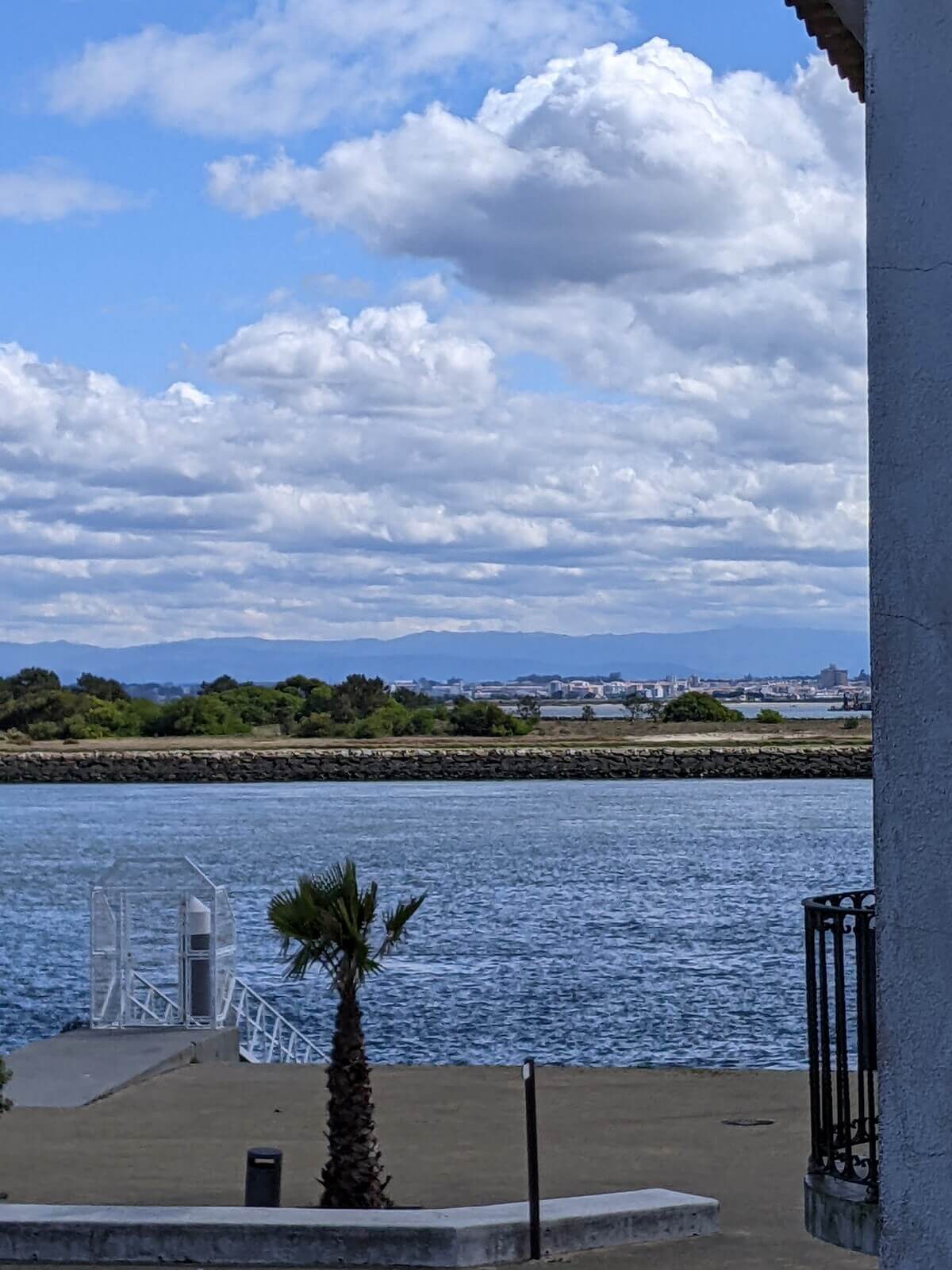 Image: The photo shows the view from the Casa dos Jacintos balcony across the Aveiro estuary on a windy day, with downtown Aveiro in the background.