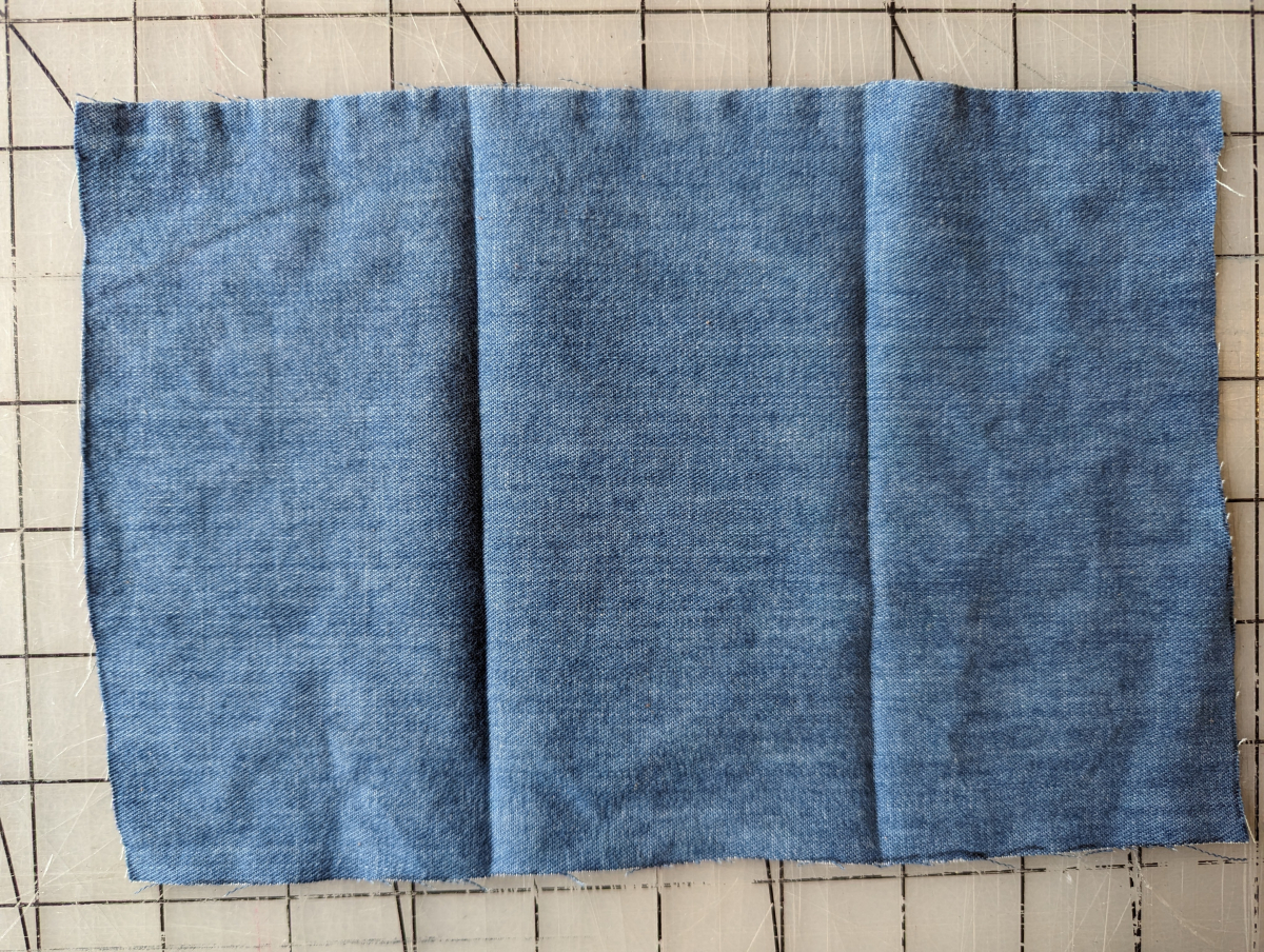 Blue denim fabric folded in thirds with creases