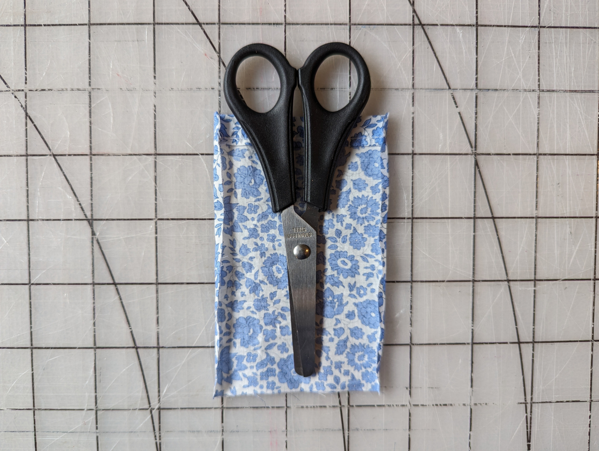 A pair of scissors lying on the scissors pocket with the edges folded in